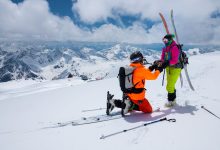 Man skiing propping to a woman on a snowy mountain